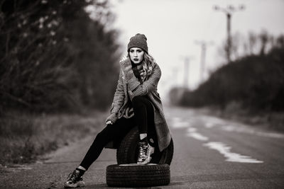 Portrait of woman sitting on road during winter