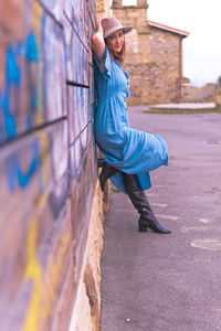 Side view portrait of woman standing by wall outdoors