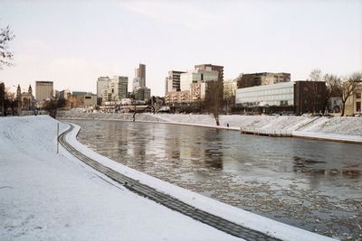 River amidst buildings in city against sky during winter