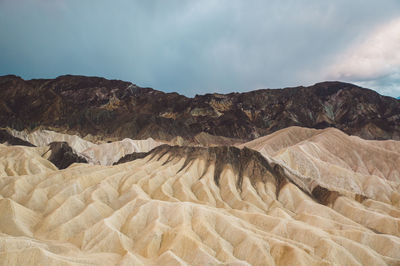 Scenic view of eroded landscape against cloudy sky at death valley national park