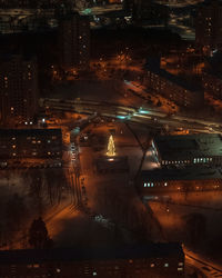 Sole christmas tree lit up in a public square at night.