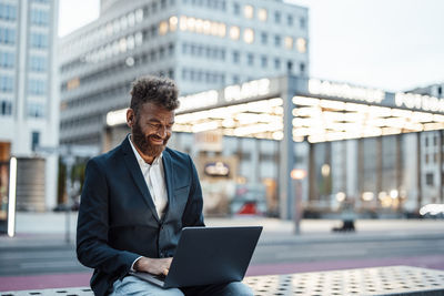 Smiling businessman working on laptop at station