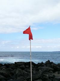 Close-up of red flag on beach against sky