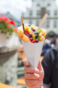 Cheat day. a man holds up a paper bag with bubble waffles with fruit. space for own ideas.