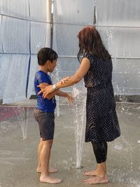 Full length of father with water splashing in rain