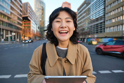 Portrait of young woman using mobile phone in city