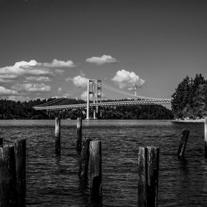 Wooden posts on bridge over river against sky