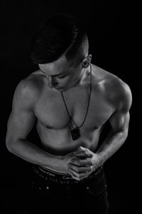 Midsection of shirtless man against black background
