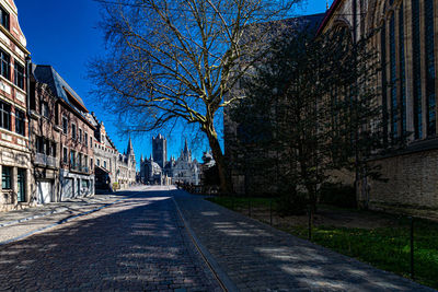 Empty road amidst buildings against clear sky