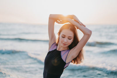 Beautiful young woman at beach against sky