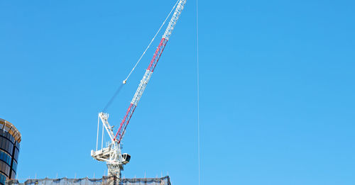 Low angle view of crane against clear blue sky