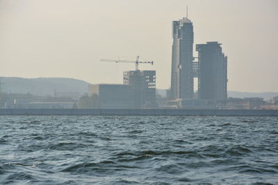 Modern buildings by sea against sky in city