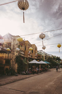 People on street amidst buildings in city against sky