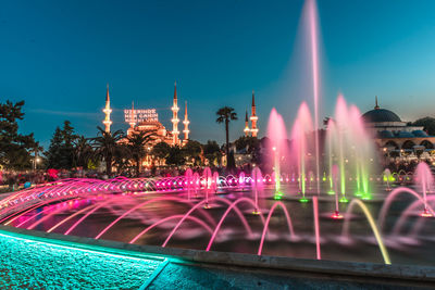 Illuminated fountain building against sky at night