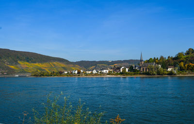 Scenic view of sea by buildings against blue sky