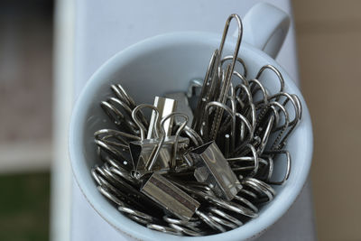 Portrait of a tiny cup filled with metal binder clips 