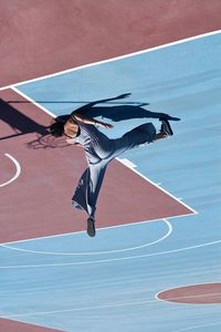 Rear view of woman jumping on court