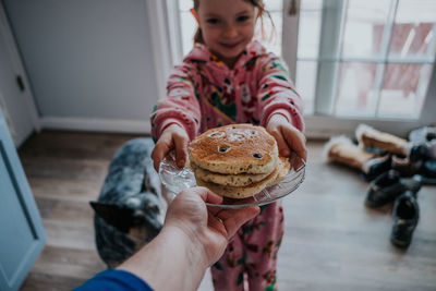 Portrait of person handing pancakes to little girl in pajamas