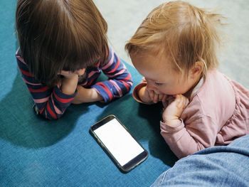 Two siblings watching something on a smartphone