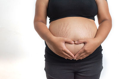 Midsection of woman touching face against white background