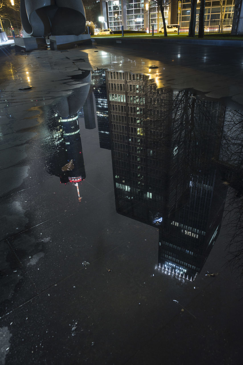 REFLECTION OF ILLUMINATED BUILDINGS ON WET STREET