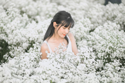 Full length of young woman on white flowering plants