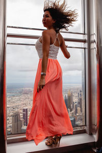 Young woman looking through window