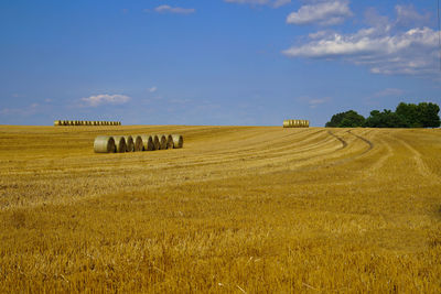 Hay bales on field against sky