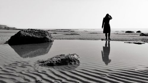 Rear view of person standing on beach against clear sky