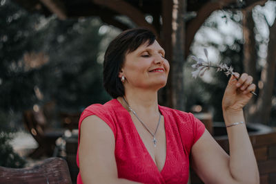 Mature woman holding flowers while sitting outdoors