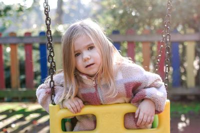 Young girl sitting on swing at park