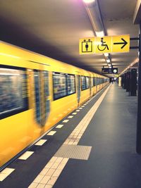 Yellow subway train in motion on platform