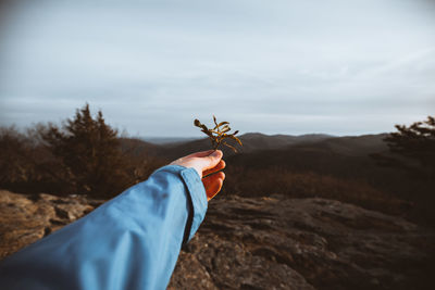 Man holding umbrella on land against sky