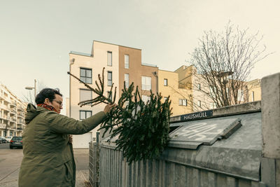 Woman putting the christmas tree in the trash at the end of the holidays