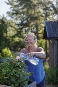 Smiling woman watering plants in garden