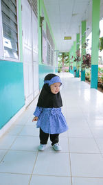 Full length of cute baby girl wearing uniform standing on floor