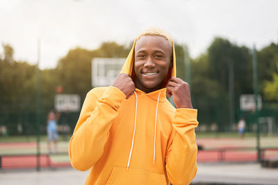 Portrait of smiling woman standing against yellow outdoors