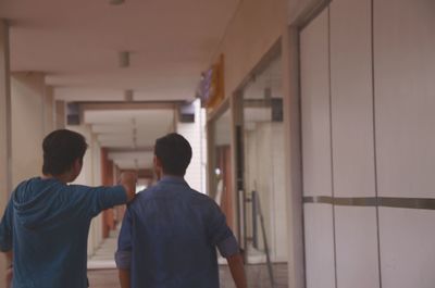 Rear view of men standing in corridor