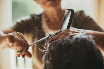 Midsection of female barber cutting male customer's hair