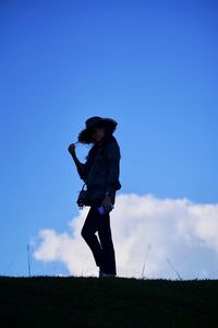 Side view of woman standing on field against sky