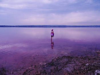 Rear view of man standing on beach against sky