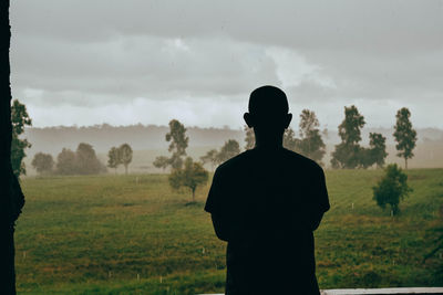 Rear view of silhouette man standing on field against sky