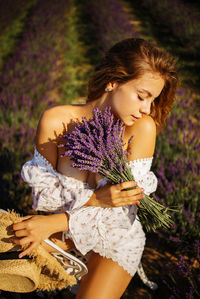Portrait of young woman sitting on lavender field
