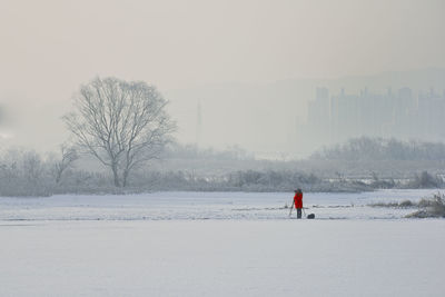 A photographer wearing red on the snowy lake