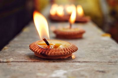 Close-up of burning diya on retaining wall