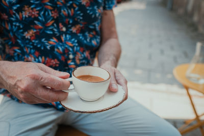 Midsection of man holding coffee cup on table