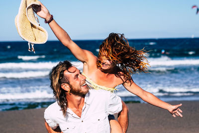 Close-up of friends at beach against sky