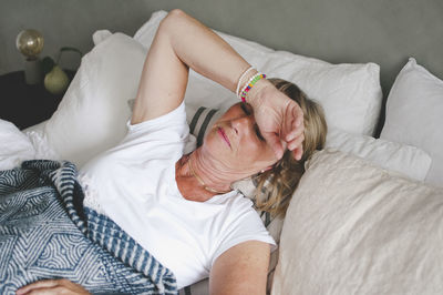 Senior woman suffering from cold lying on bed at home