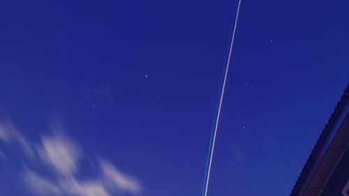 Low angle view of vapor trails against blue sky