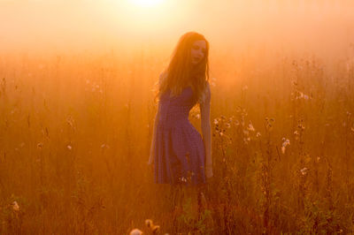 Woman standing on field during sunset